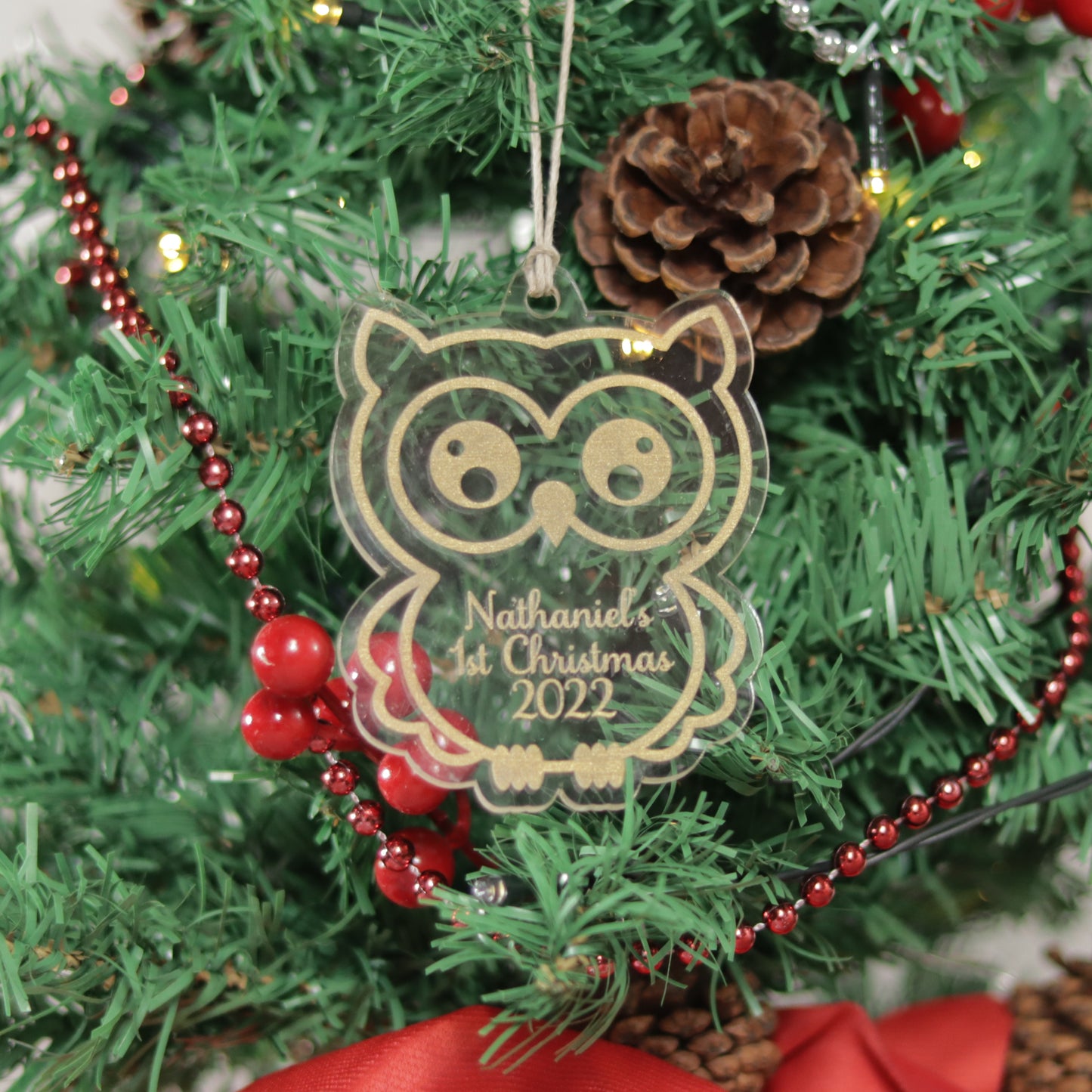 Owl shaped clear acrylic ornament hung on a mini Christmas tree. Nathaniel's 1st Christmas 2022 is etched in the ornament with gold acrylic paint filling.